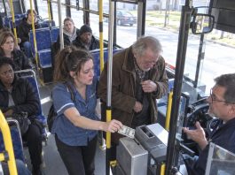 She almost walked past the elderly man because she was already late getting home, but something made her turn around and quietly pay his fare. The next day, flashing police lights stopped outside her house, and when she opened the door, an officer said something she never expected to hear.