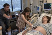 Doctors had almost stopped expecting Emily to wake before giving birth. But on one rainy afternoon, a seven-year-old girl quietly entered her room, spread dark soil across her pregnant belly, and whispered something no one else could hear. Emily’s husband was about to stop her—until he saw his wife’s hand twitch.