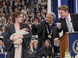 Holding my two-week-old baby at graduation, I watched my ex grab the microphone and shout, “Look at this pathetic dropout!” Five hundred guests laughed. I stood frozen until the university president interrupted. “She’s our valedictorian—and the sole heir to the $20 million trust funding this university!”